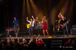 photo d'un concert d'un groupe d'artistes devant des spectateurs qui applaudissent